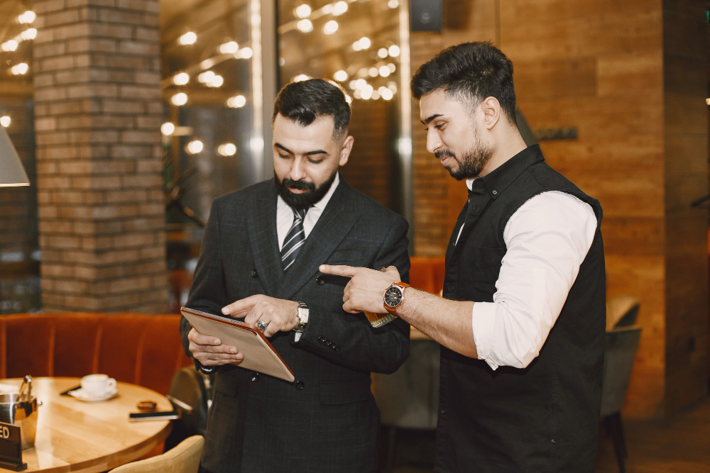 Restaurant manager and staff member discussing the day's orders on a tablet